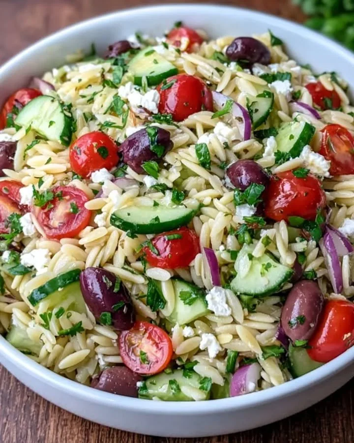 Mediterranean orzo salad with vegetables and herbs in a bowl.