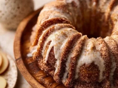 Slice of apple cider donut cake topped with glaze and cinnamon