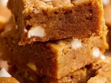 Delicious pumpkin blondies topped with nuts and spices on a wooden table