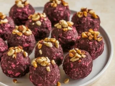 Homemade banana and beetroot balls on a wooden plate with fresh ingredients.