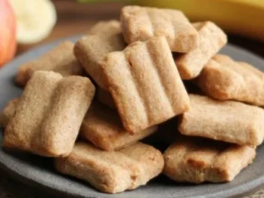 Homemade apple and banana dog treats on a wooden surface