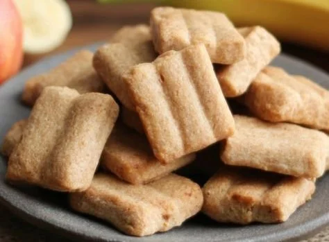 Homemade apple and banana dog treats on a wooden surface