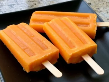 Homemade pumpkin and turmeric pupsicles for dogs on a wooden surface