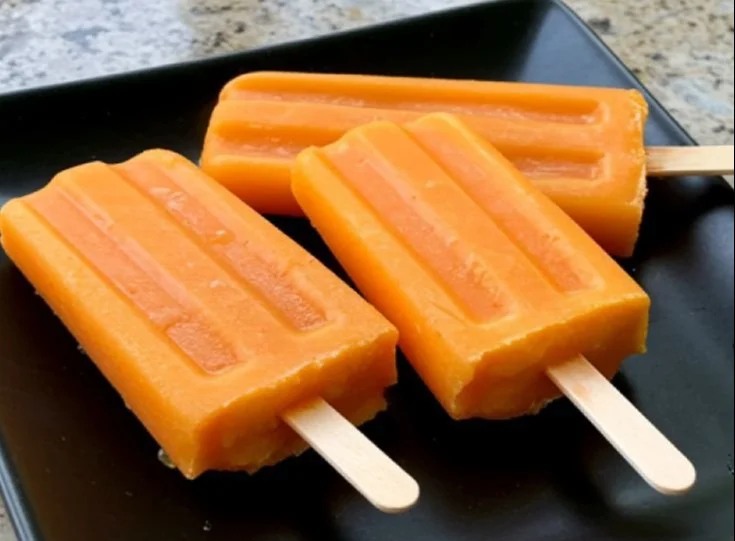 Homemade pumpkin and turmeric pupsicles for dogs on a wooden surface
