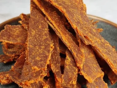 Homemade dehydrator pumpkin leather dog treats on a wooden kitchen table