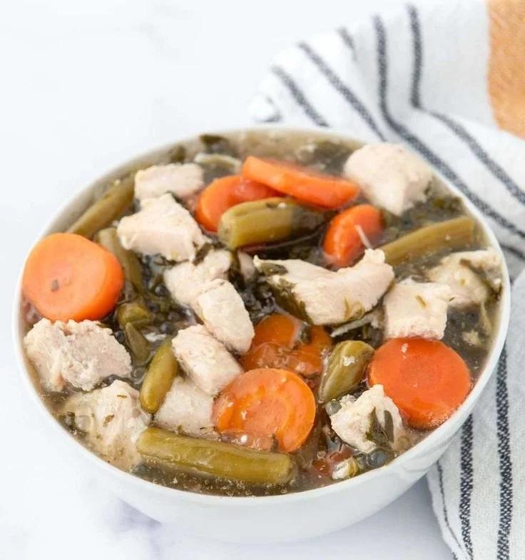 Homemade chicken stew for dogs in a bowl with fresh ingredients