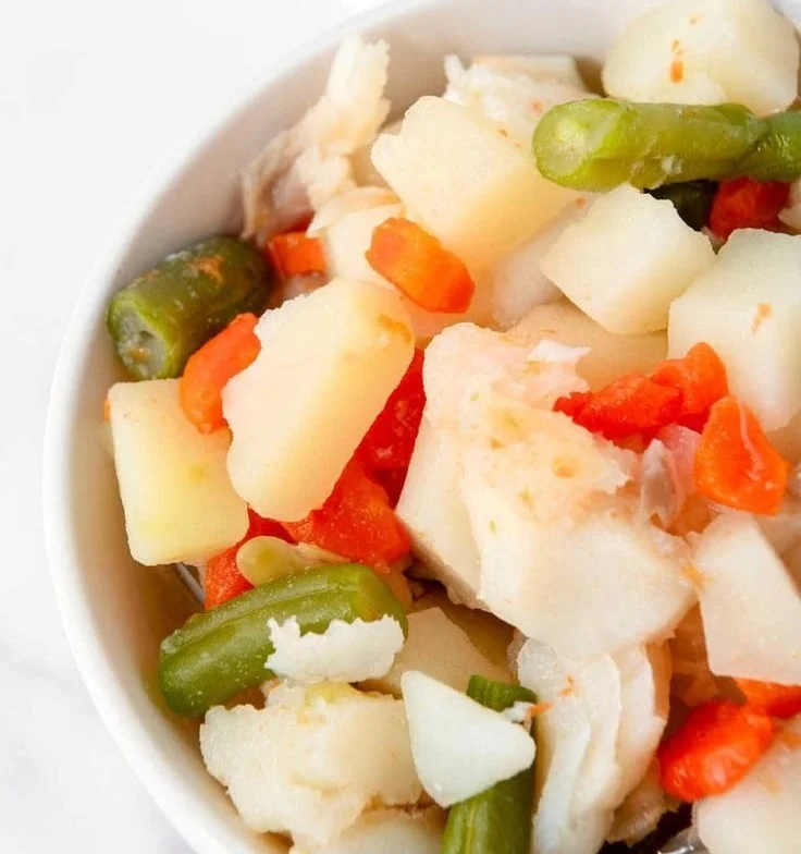 Homemade fish stew for dogs in a bowl with fresh ingredients.