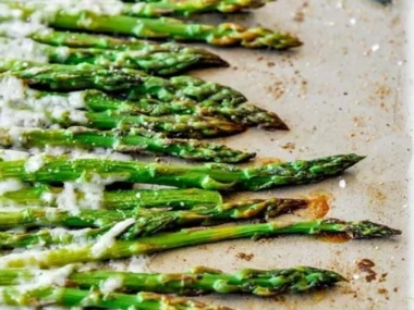 Plate of roasted Parmesan asparagus with a golden crispy topping.
